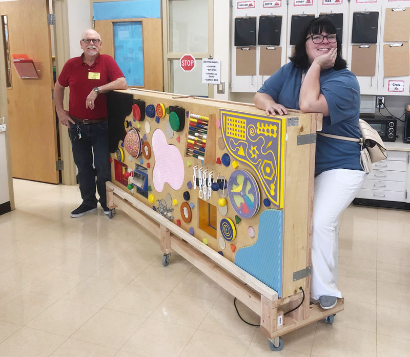 Volunteer David Durbin delivers the multisensory board with the rolling stand that he built for Mrs. Wilson’s Washington Center class. 