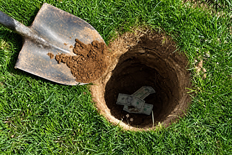 Shovel beside hole with dollar bills