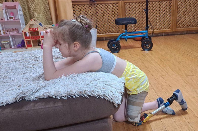 Ten year old Maryna kneels beside her bed and prays for the war in Ukraine to end