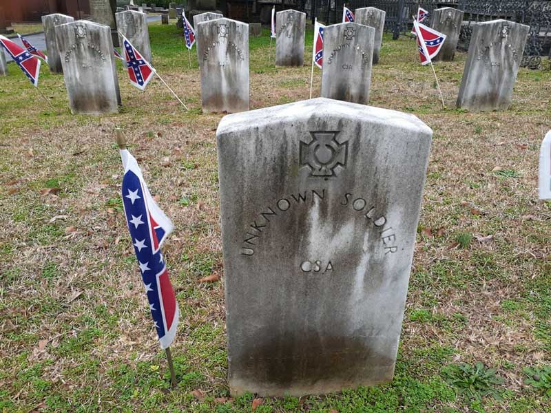 Confederate flags stand sentinel beside graves of Confederate veterans interred in Springwood Cemetery.