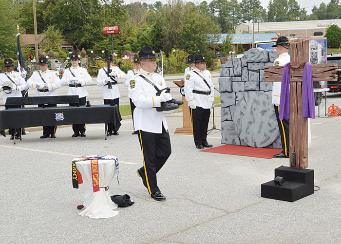 This Ceremony is in honor of a fallen soldier.  The soldier’s unpolished boots are carried by an  Honor Guard member to be placed on the wooden block in front of the cross.
