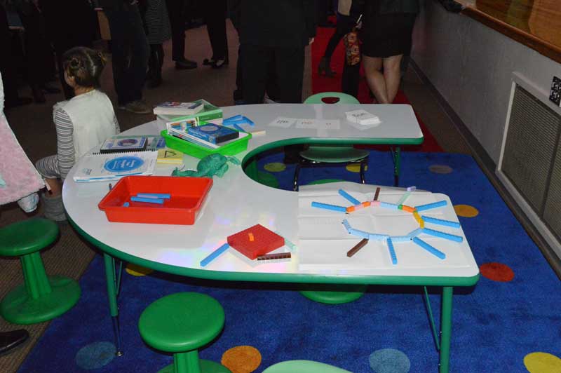 A special-designed two-part table allows the teacher to be able to reach out to all the students sitting at the table. This gives a personal one-on-one education experience.