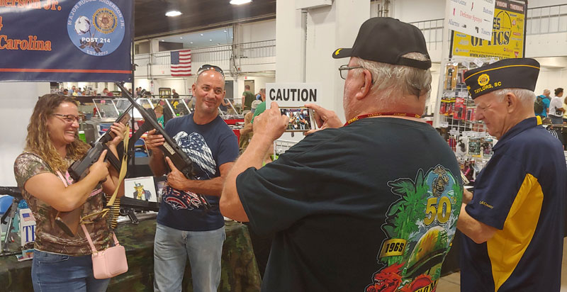 Major Rudolf Anderson, Jr. Post 214 Sergeant-at-Arms Ed Collins and Commander Jack Dorn. Photographed visitors tot he American Legion table at August Gun Show. Holding weapons from the Cecil D. Buchanan Museum of Military History.