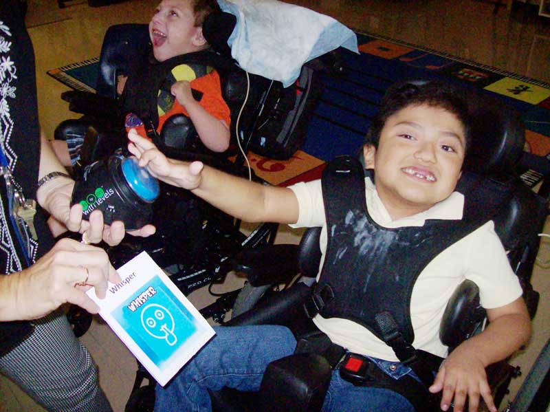 Washington Center students press an augmentative device to hear and identify ways people use their voices during Music Class.